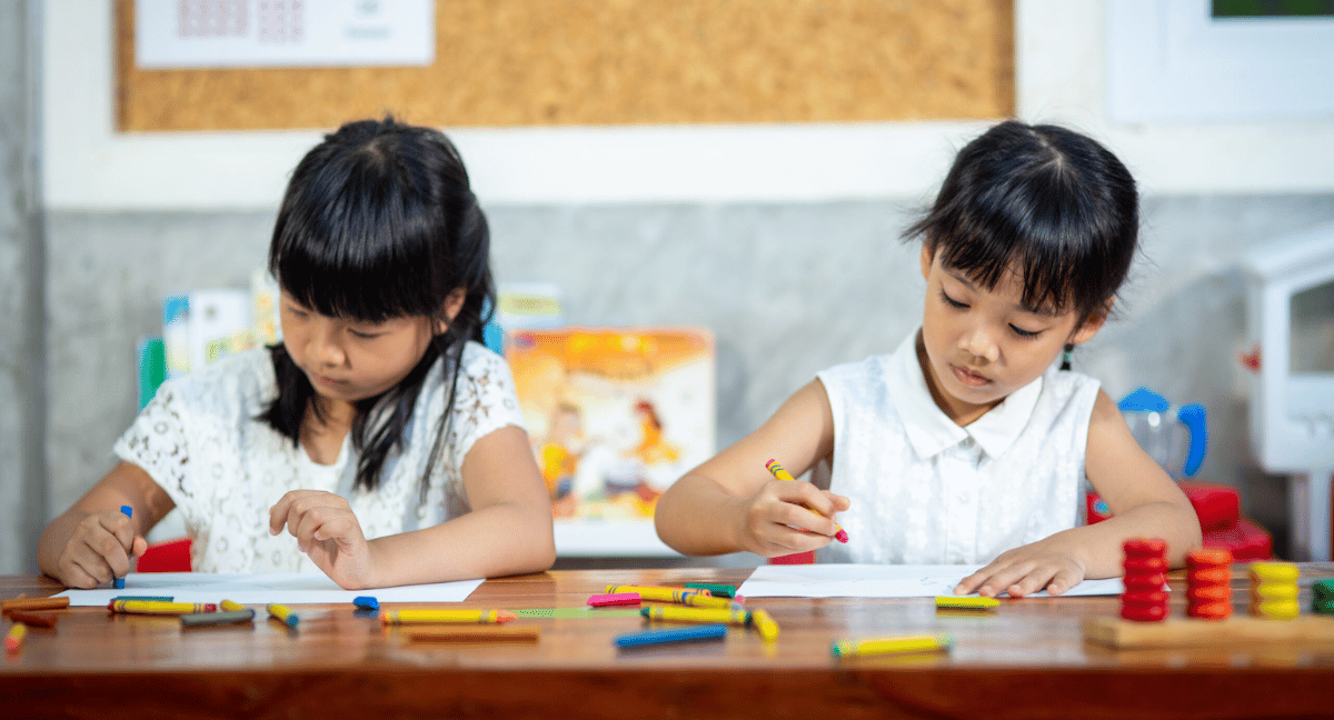two preschool girls drawing with crayons