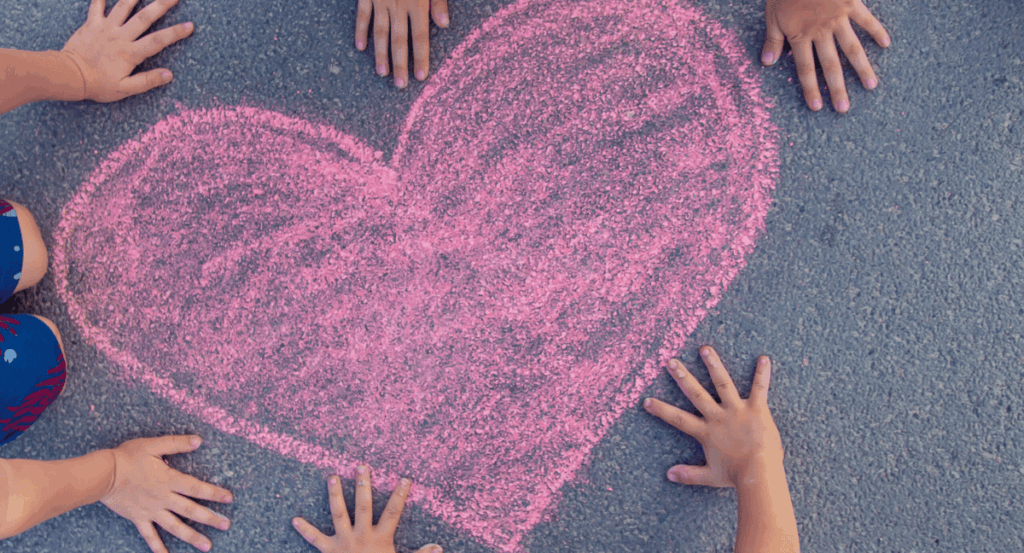 children draw a heart in pink chalk
